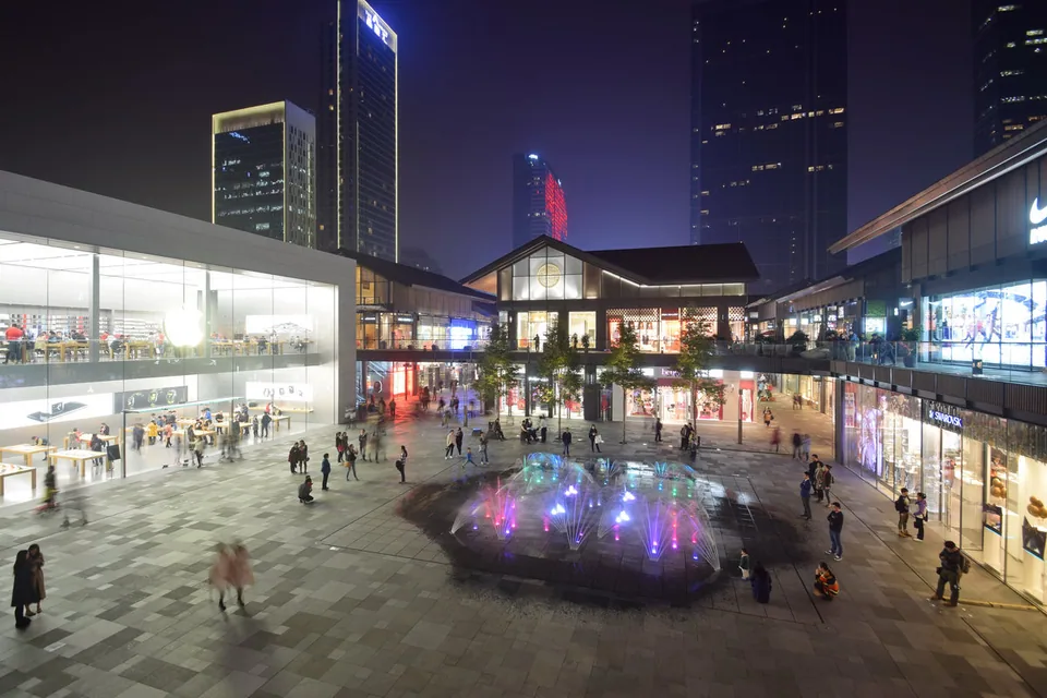 成都太古里东广场夜景，中央喷泉、两侧商铺和二层步行空间。