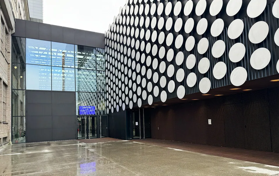 左侧旧电缆厂砖墙与右侧圆形饰面新建筑之间，是通向玻璃院落的共同入口。